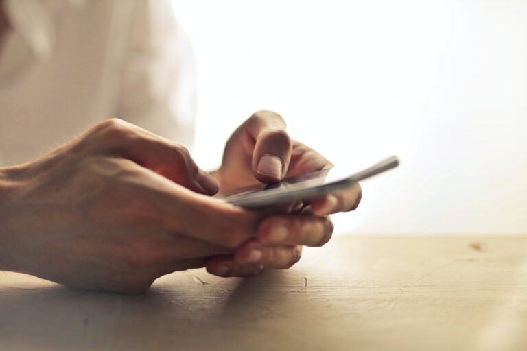 Männerhände halten ein Smartphone und tippen